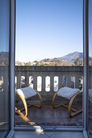 Ein Balkon mit zwei Schaukelstühlen, Blick auf Berge und einem klaren Himmel.