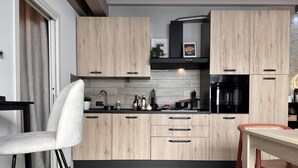 Uma cozinha moderna com armários de madeira, um fogão preto e uma área de refeições com uma cadeira vermelha.