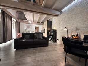Ein modernes Wohnzimmer mit einer Couch, einem Esstisch und einer Küchenzeile im Hintergrund.