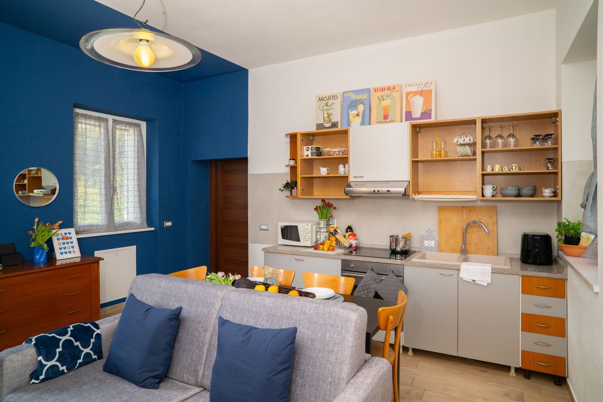 Una cocina moderna con comedor, paredes azules y armarios de madera.