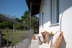Ein Balkon mit Holztisch, Stuhl und einer Topfpflanze.