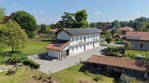 A two-story building with a balcony, solar panels, and a gravel driveway. - Tramonto MXP Nature Living, WiFi & Coffe (Somma Lombardo)