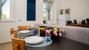 En matplats med ett bord för fyra personer, en soffa, ett kylskåp och en kaffebryggare.
