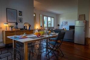A modern kitchen with a dining area, wooden cabinets, and a refrigerator.
