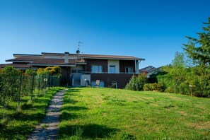 Una casa a due piani con un ingresso anteriore ben visibile, un'antenna parabolica e un vialetto che conduce alla porta.