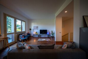 A living room with a sofa, a coffee table, a TV, and a large window.