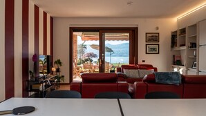 Ett vardagsrum med en röd soffa, en tv och ett bord med ett paddelspel på.