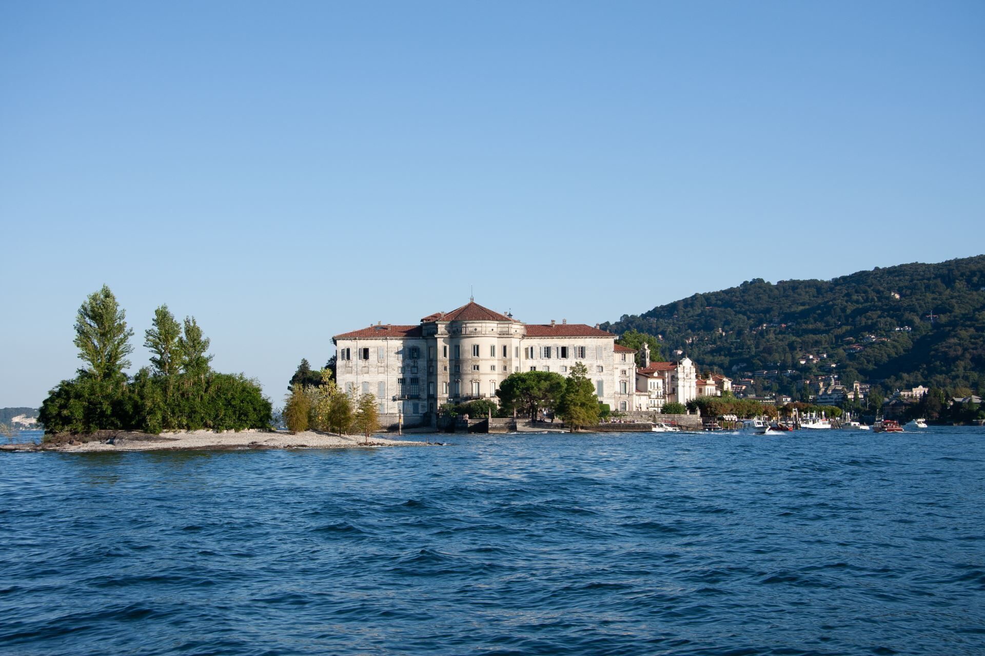 Ein großes, historisches Gebäude mit rotem Ziegeldach, auf einer kleinen Insel inmitten von Wasser gelegen.