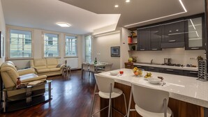A modern kitchen with dark cabinets, a bar area with stools, and a dining area with a sofa and chairs. - Mazzini 1 - Smart Flat 2 bedrooms Garage (Gallarate)