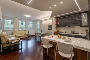 A modern kitchen with dark cabinets, a bar area with stools, and a dining area with a sofa and chairs. - Mazzini 1 - Smart Flat 2 bedrooms Garage (Gallarate)