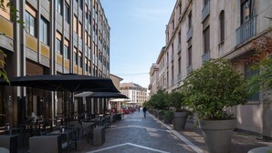 A narrow cobblestone street lined with outdoor seating and potted plants. - Mazzini 1 - Smart Flat 2 bedrooms Garage (Gallarate)
