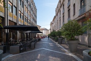 A narrow cobblestone street lined with outdoor seating and potted plants. - Mazzini 1 - Smart Flat 2 bedrooms Garage (Gallarate)