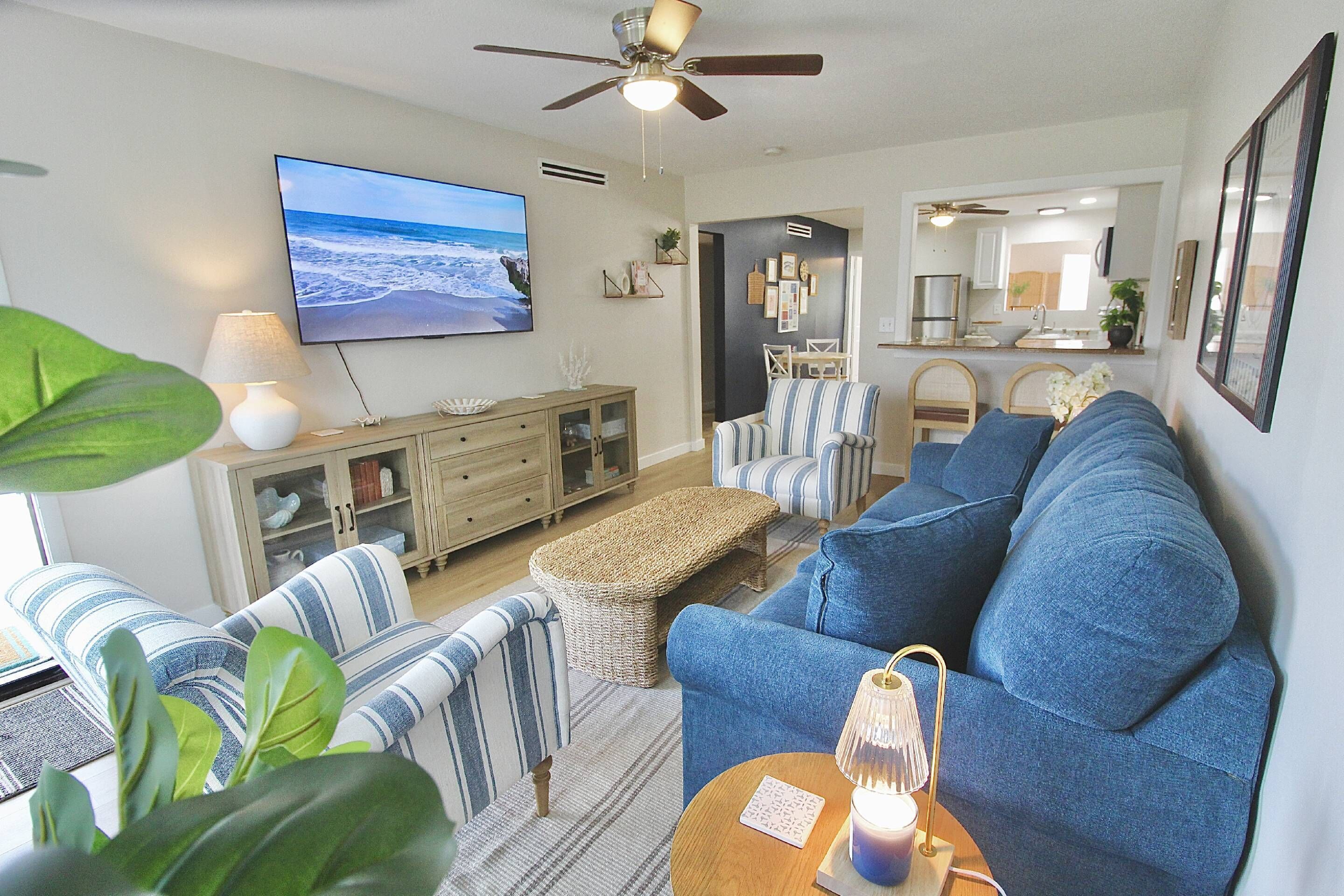 Ein Wohnzimmer mit Fernseher, Sofa, Sesseln und Deckenventilator.