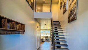 Eine Treppe mit Holzbodenstufen und Metallgeländern, die zu einer zweiten Etage mit Geländer führt.