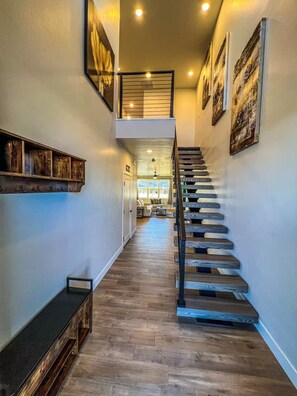 Eine Treppe mit Holzbodenstufen und Metallgeländern, die zu einer zweiten Etage mit Geländer führt.