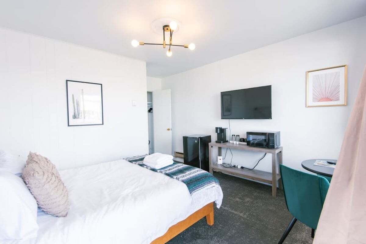 A hotel room with a bed, a desk with a chair, a television, and a coffee machine.