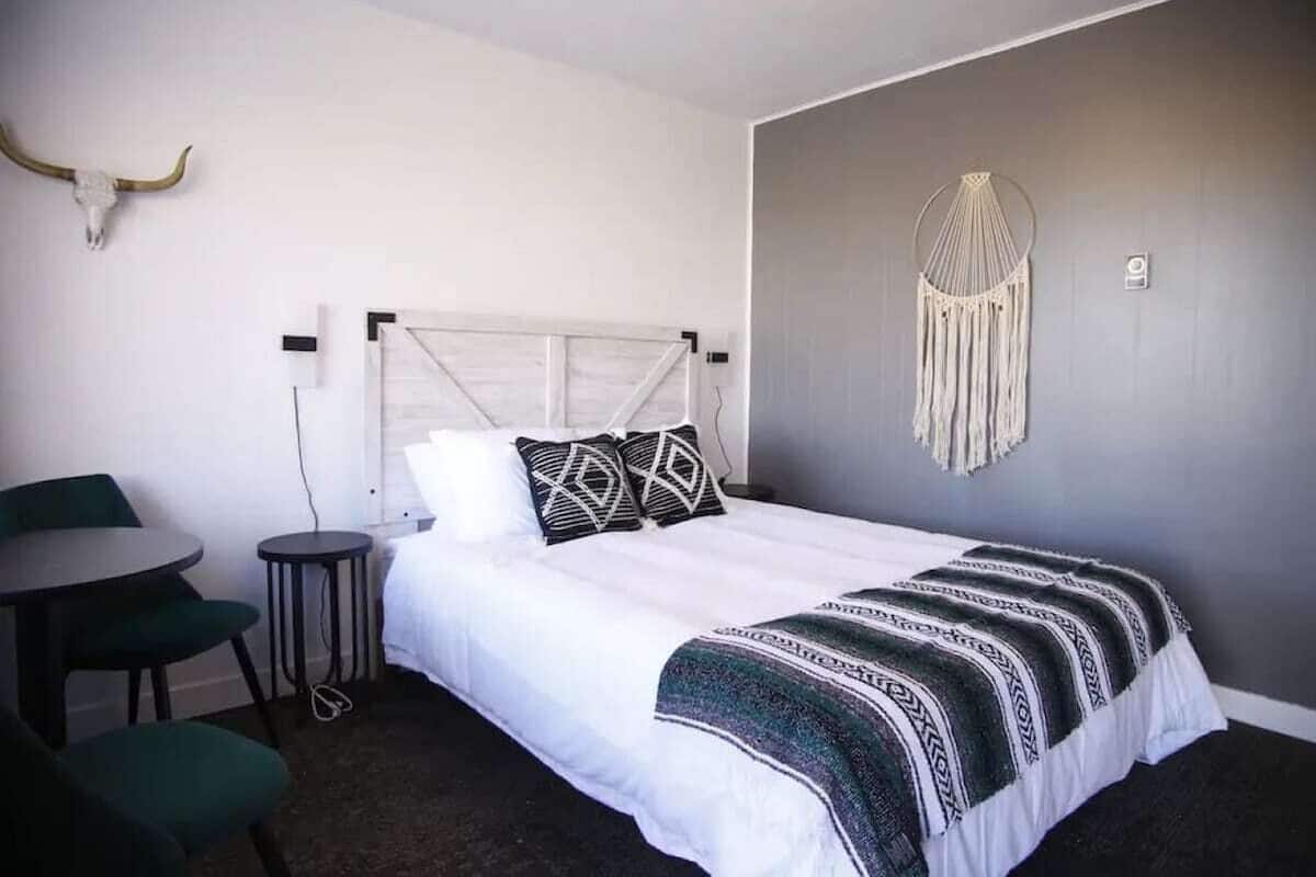A bedroom with a white bed, a round table, and two chairs.