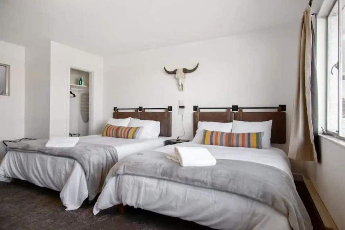 A hotel room with two beds, each with a striped pillow and a white towel.