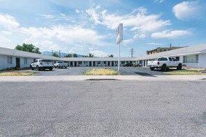 A motel with a central parking area, a row of single-story buildings, and a clear sky. - AEA - Fillmore UT (Fillmore)