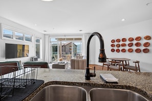 A modern kitchen with granite countertops, a stainless steel sink, and a black faucet. - Lakefront Pool and Lake View 2 Bdrm 4205 (West Kelowna)