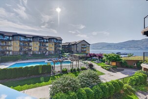 Um edifício residencial com piscina, vista para a água e uma montanha ao fundo.
