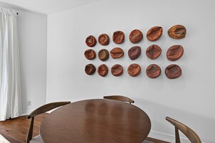Uma sala de jantar com uma mesa de madeira redonda e quatro cadeiras, uma parede branca com bolas de basquete dispostas em padrão de grade.