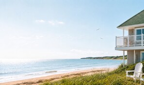 En fastighet som ligger vid stranden, med en balkong med utsikt över havet, en stol och en staty.
