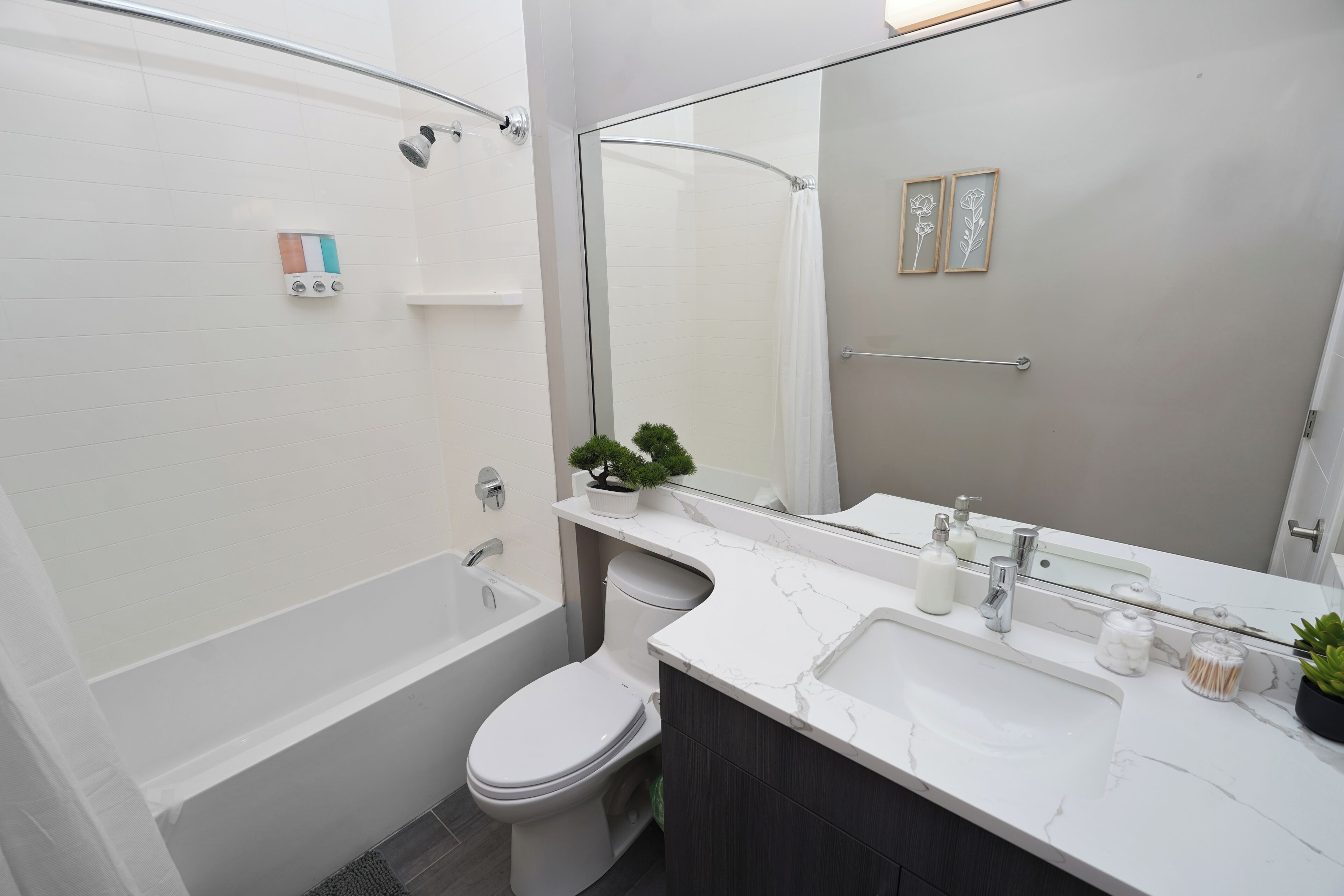 Ein modernes Badezimmer mit Badewanne, Toilette und einem großen Spiegel.
