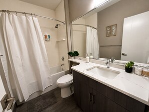 A bathroom with a bathtub, toilet, sink, and shower curtain. - Spacious 4BR West Loop Retreat w/Optional Parking (Chicago)