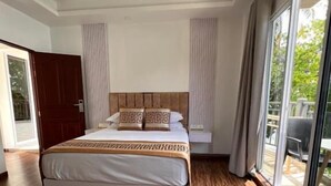 A bedroom with a large bed, a chair, and a view through a glass door. - Alma Maldiva beach hotel (Dhidhdhoo)