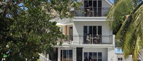 Un edificio de dos plantas con balcón, ventanas amplias y fachada de piedra.