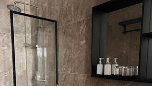 A modern bathroom with a glass-enclosed shower, a white toilet, a black sink with a black countertop, and a mirror above the sink. - Alma Maldiva beach hotel (Dhidhdhoo)
