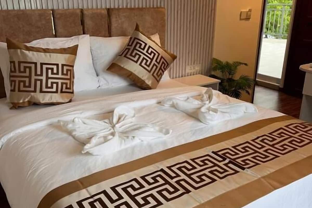 Un lit bien fait, recouvert d’une couvre-lit à motifs, avec des oreillers à dessins géométriques et une tête de lit adossée à un mur.