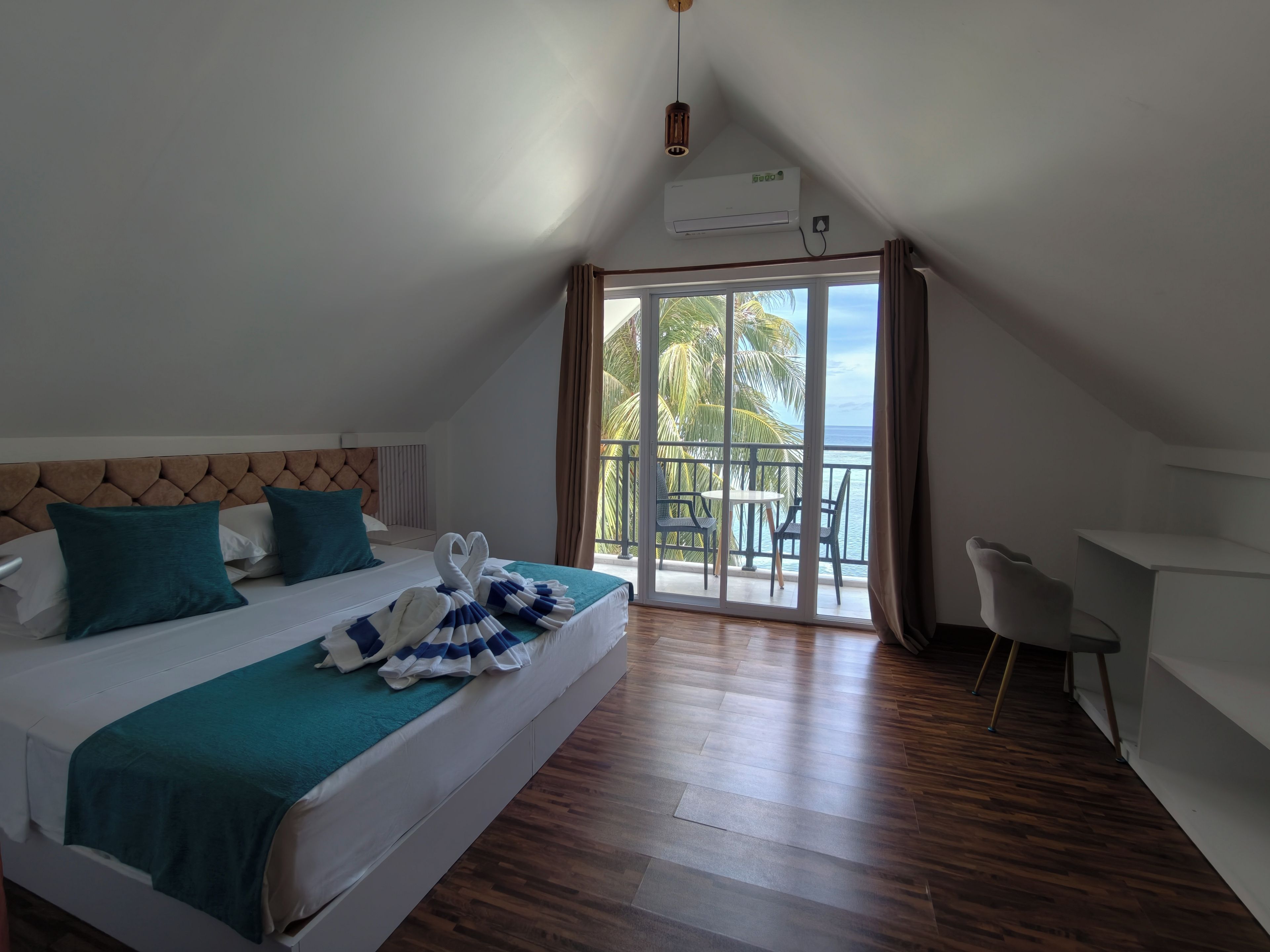 Habitación de hotel con cama, escritorio, balcón y vistas al mar, además de aire acondicionado.