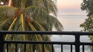 A balcony with a view of the ocean and palm trees. - Alma Maldiva beach hotel (Dhidhdhoo)