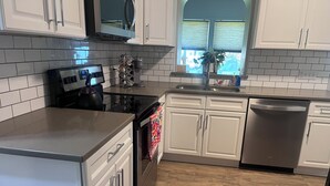 A kitchen with white cabinets, a stainless steel stove, and a dishwasher. - Stone's Throw Bungalow - Cozy and Convenient in Chambersburg, PA (Chambersburg)