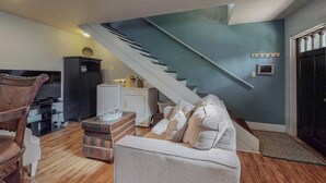 Een woonkamer met een trap, een televisie, een bank en een kast.
