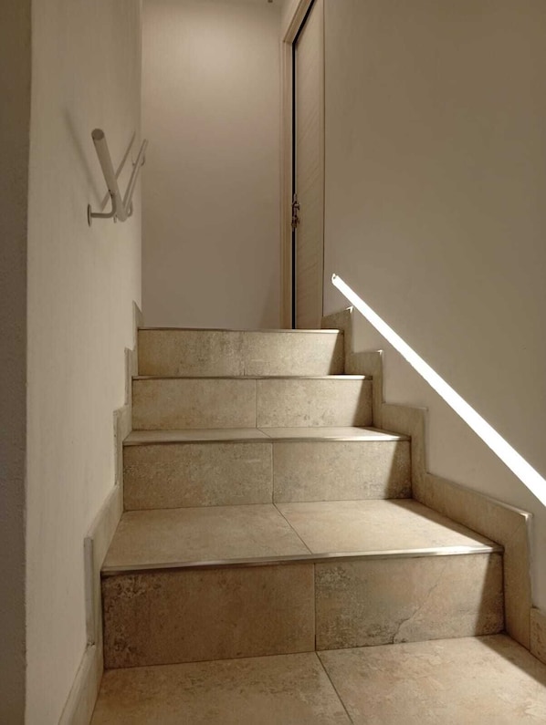 A staircase with beige tiles, a handrail, and a door at the top. - Il Sassolino - Hostel (Riomaggiore)