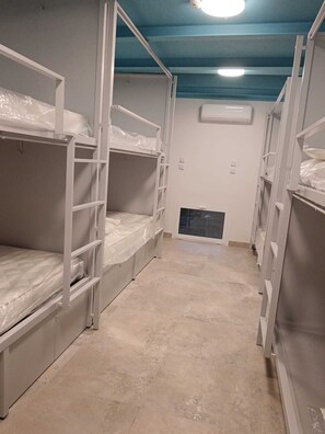 A bunk room with bunk beds, a tiled floor, and an air conditioning unit on the wall.