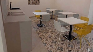 A room with a kitchen area, white tables, and yellow chairs. - Il Sassolino - Hostel (Riomaggiore)
