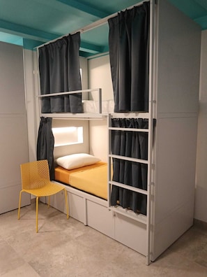 A bunk bed with curtains, a chair, and a bedside table. - Il Sassolino - Hostel (Riomaggiore)