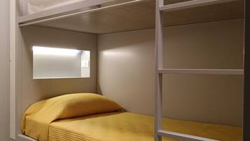 Een stapelbed met een onderbed en een bovenbed, beide met witte beddengoed.