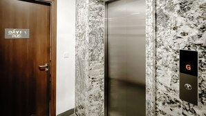 An elevator with a digital display, a marble wall, and a wooden door with a sign. - 2BR 2BTR Penthouse w/ Kitchen & BBQ Terrace in Long Bien (Hà Nội)