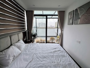 Et hotelværelse med seng, ventilator, udsigt over byen og en balkon med planter.