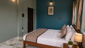 A bedroom with a bed, a bedside lamp, a potted plant, and a framed picture on the wall. - Sandhya Guest House (Ekangardih)