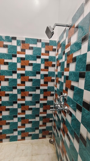 Ein Duschbereich mit einer mit geometrischen Mustern versehenen Fliesenwand.
