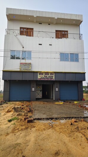 A multi-story building with a signboard for KidPulse Private Limited, a large open entrance, and a construction site in front. - Sandhya Guest House (Ekangardih)