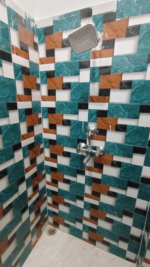 A shower area with a tiled wall featuring a geometric pattern.