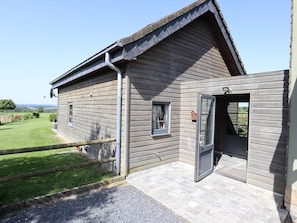 A wooden building with a sloped roof, a door, and a small window.
