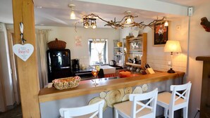 A kitchen with a central island, bar stools, a coffee machine, and a decorative ceiling light.